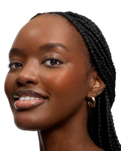 Mujer sonriente con trenzas largas y labios brillantes.
