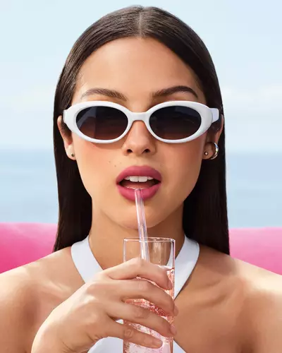 Olivia Rodrigo con gafas de sol blancas y un look de labios malva.