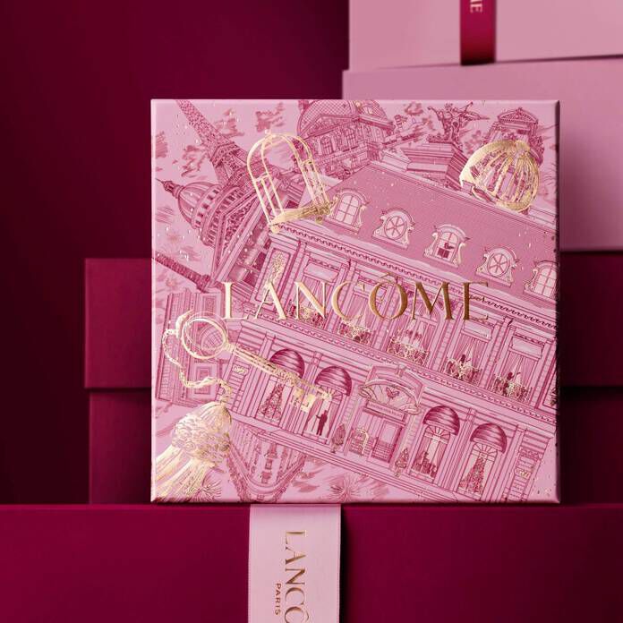 Imagen de una caja de regalo rosa Lancome de pie delante de un monton de cajas de regalo rosas y rojo oscuro, sobre un fondo rojo oscuro.