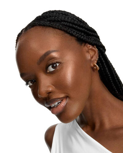 Mujer sonriente con largas trenzas y piel radiante.