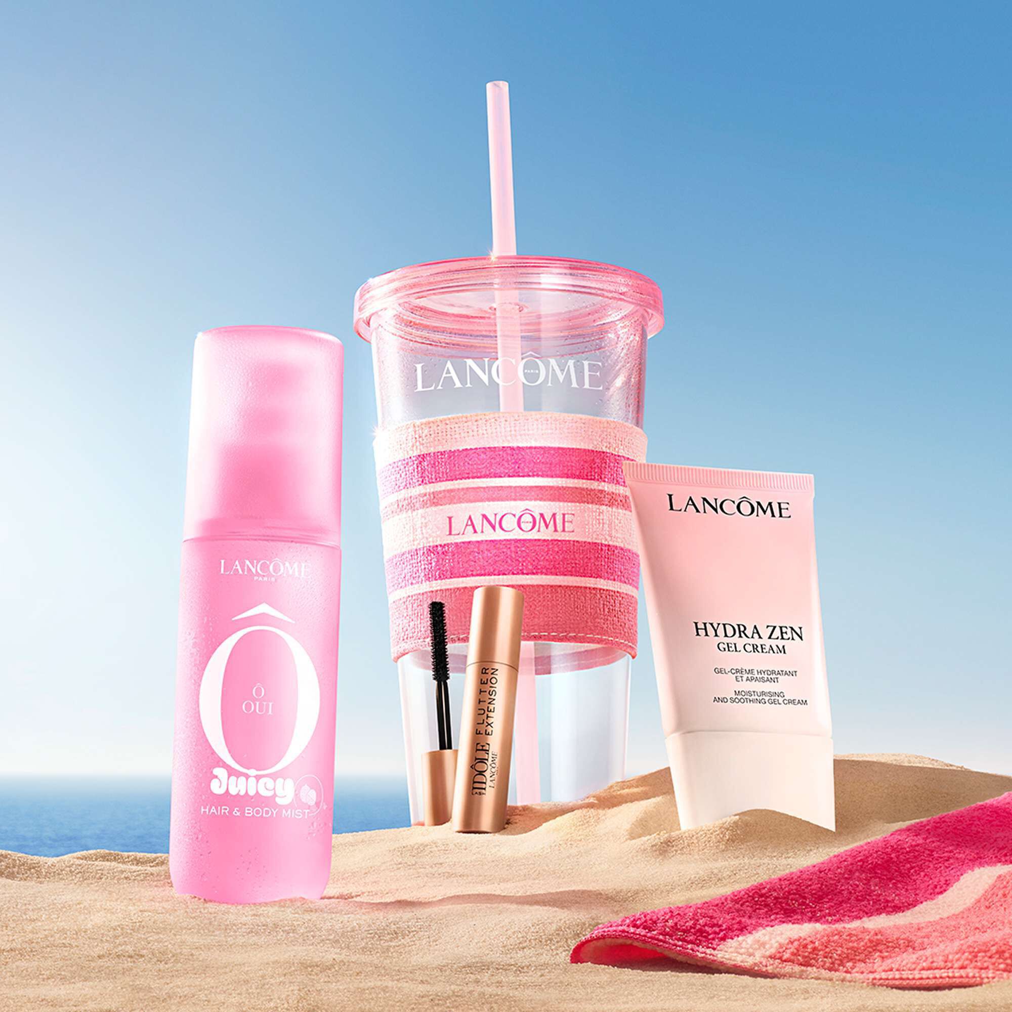 Una foto de estilo de vida del decorado de belleza de Lancome expuesta en una playa de arena bajo un cielo azul.