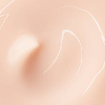 Textura suave y cremosa de un producto de maquillaje en tonos nude, con lineas sutiles sobre un fondo claro.