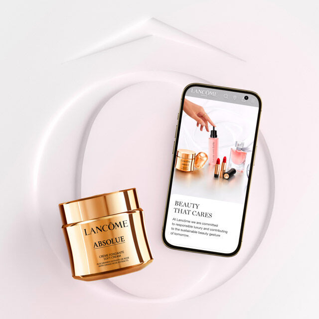 Frasco de crema de Lancome sobre una superficie blanca, junto a un telefono movil que muestra informacion sobre productos de belleza.
