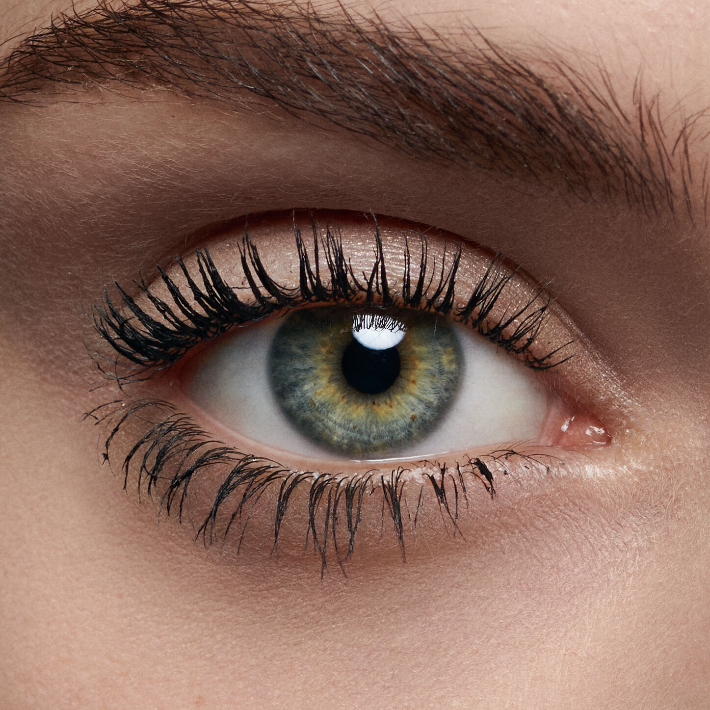 Ojo humano en primer plano, con iris verde y marron, pestanas largas y piel clara.