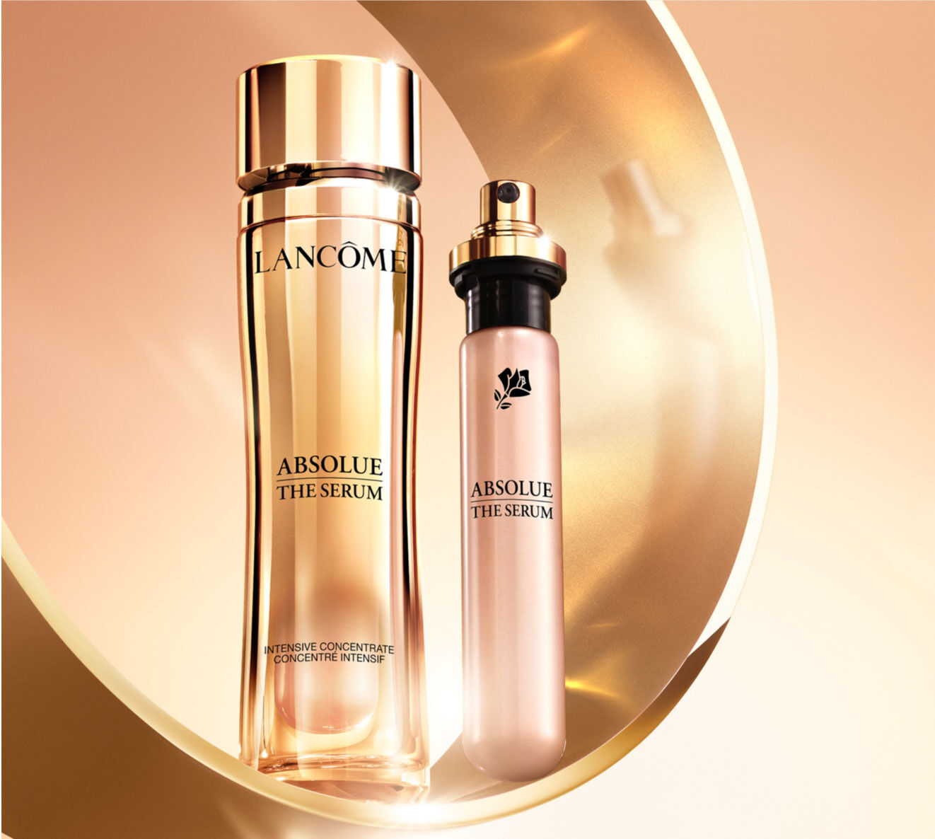 Imagen de dos frascos de serum de la marca Lancome, presentados sobre un fondo dorado. El producto principal es un frasco alto y elegante de "Absolue The Serum", junto a un frasco mas pequeno del mismo producto.