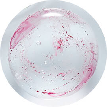 Detalle de un liquido transparente con manchas y burbujas de color rojo, en un contenedor circular.