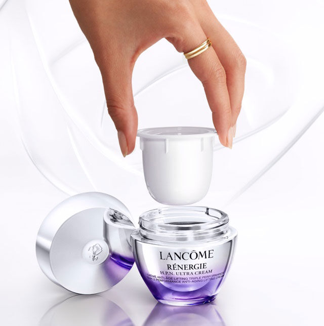 Un frasco de crema de Lancome Renergie con la tapa levantada, mientras una mano sostiene la tapa.