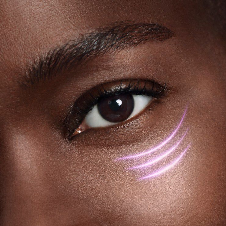 Primer plano de un ojo con un brillo sutil y tres lineas moradas pintadas en la mejilla, creando un efecto artistico.