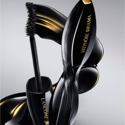 Imagen de un envase de rimel "Hypnose Drama" de Lancome, con un cepillo de aplicacion, todo en un fondo gris suave.