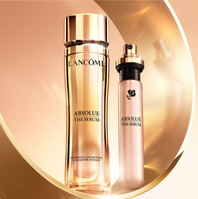 Frascos de serum de la linea "Absolue" de Lancome, uno grande y otro mas pequeno, con un fondo en tonos dorados.