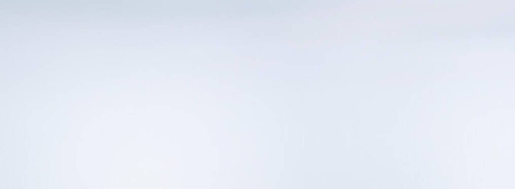 Tres frascos de perfume elegantemente dispuestos sobre una superficie blanca, acompanados de una flor blanca.