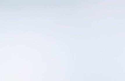 Tres frascos de perfume elegantemente dispuestos sobre una superficie blanca, acompanados de una flor blanca.